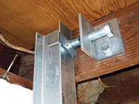 Securing the i-beam system to the top of the floor joist in a foundation wall repair in Burlington.