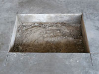 Creating the hole in the garage slab floor during the wall anchor installation in Clarington.